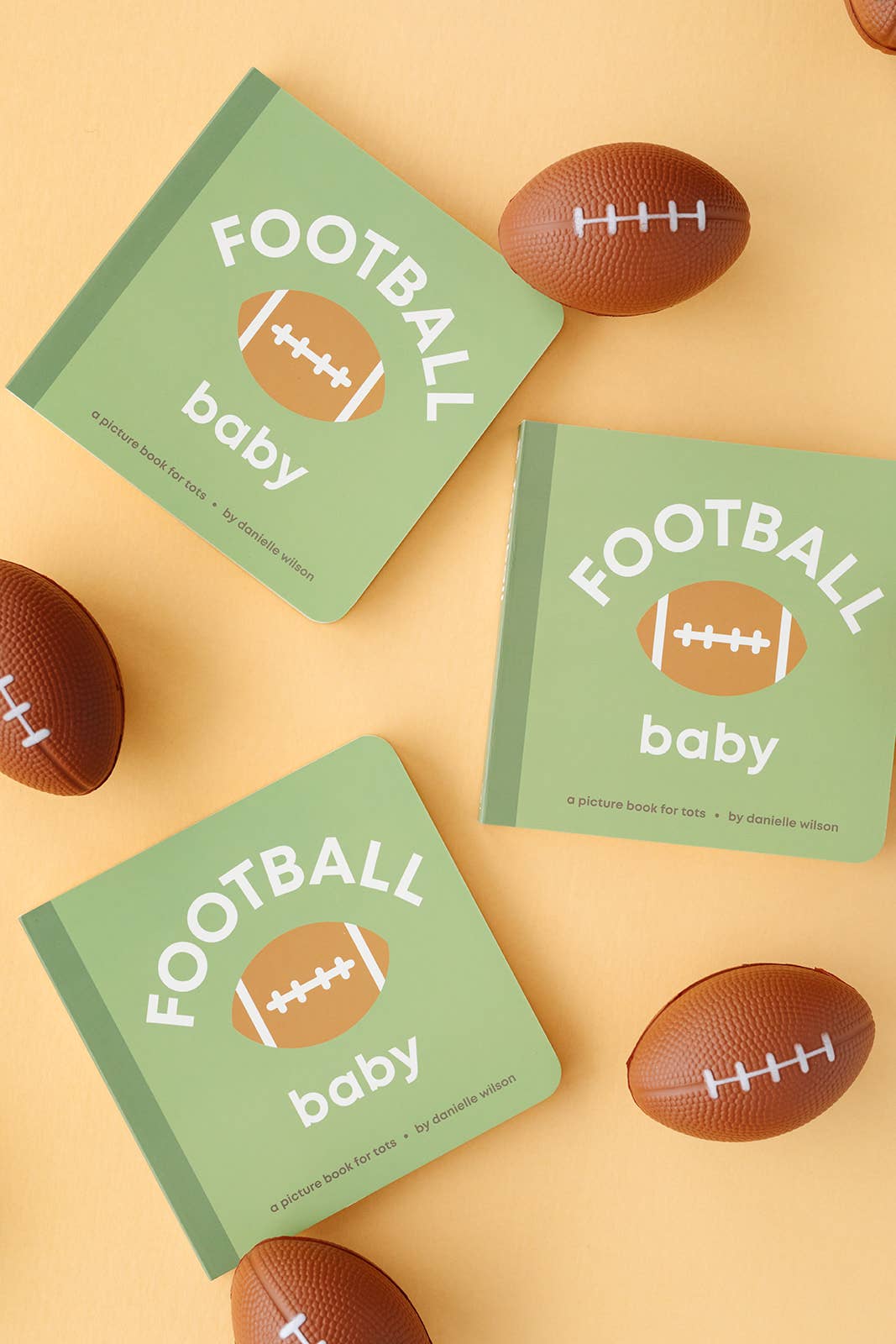 'Football Baby' books on a beige background with footballs around them.