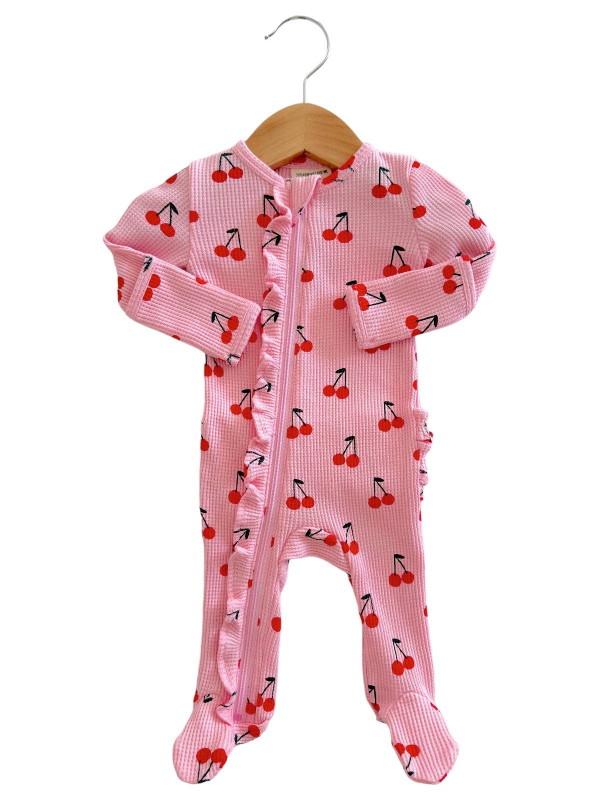 Pink baby onesie with cherry pattern on a hanger against a white background