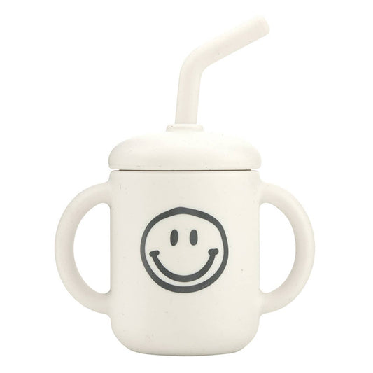 White sippy cup with smiley face design on a white background